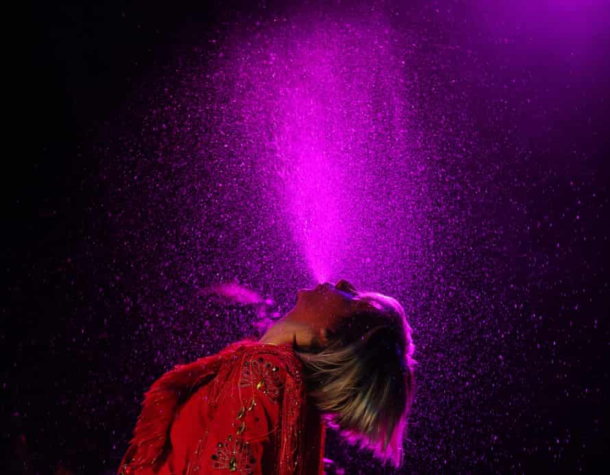 Karen O sprays water up into the air from her mouth on stage