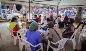 People wait to receive coronavirus vaccinations at a streetside vaccination tent in downtown Kampala, Uganda.