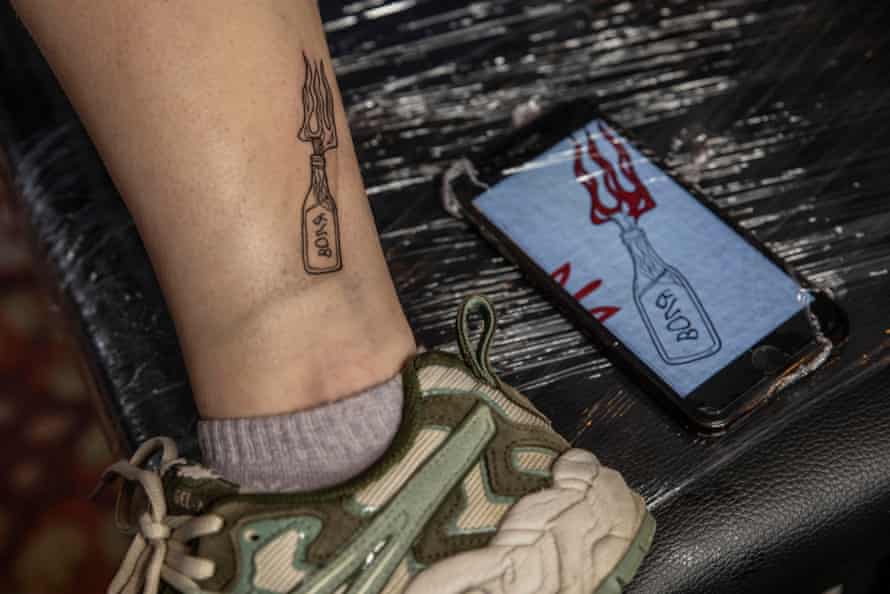 A Molotov cocktail with a stylized flame-shaped coat of arms of Ukraine tattooed on a young girl's ankle during the tattoo marathon