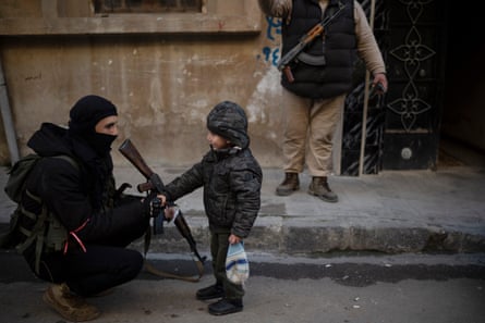 A member of the new security forces shakes hands with a boy during an operation to detain men suspected of being part of militias or loyalist soldiers of the ousted president