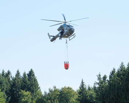 A Belgian helicopter prepares to drop water over a wildfire in the High Fens.