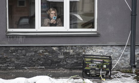 A woman is on her phone behind a generator as the power is out in Kyiv.