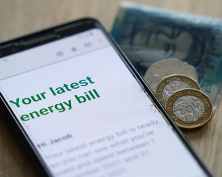 an energy bills notice on a smartphone with pound coins and £5 notes beside it