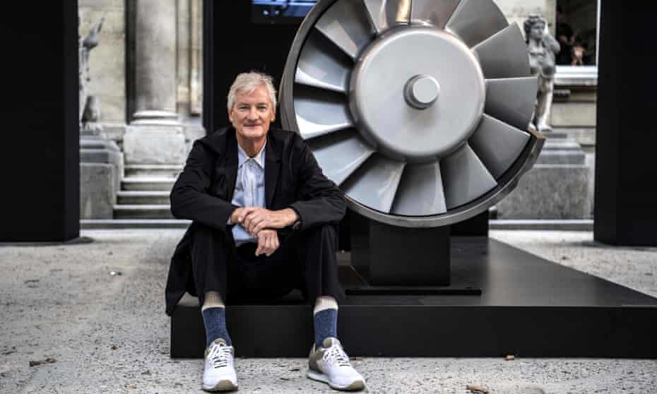 James Dyson poses next to the model of an engine.