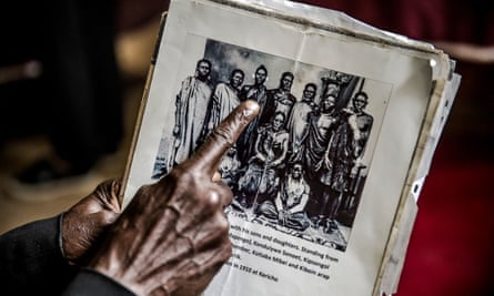 A man affected by the forcefully evictions shows a picture of his relatives and ancestors