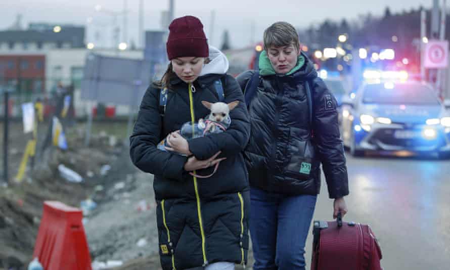 A girl holds a dog as she arrives at the border crossing in Medyka, south-eastern Poland, from Ukraine.