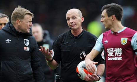 Mike Dean (centre) offers his verdict at half-time on the VAR decision against Bournemouth that enraged Eddie Howe (left) in the defeat by Burnley on Saturday.