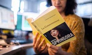 A woman sitting, holds and reads the book “Le Consentement” (“The consent”) from French writer Vanessa Springora.