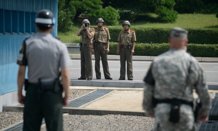 North Korean soldiers (C) take photos towards a South Korean soldier (L) and a US soldier (R) standing before the military demarcation line separating North and South Korea.