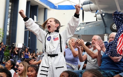 A child dressed in an astronaut costume reacts as Artemis II splashes down