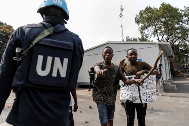 A UN soldier and demonstrators with a poster protesting against the Monusco peacekeeping mission in Goma in July
