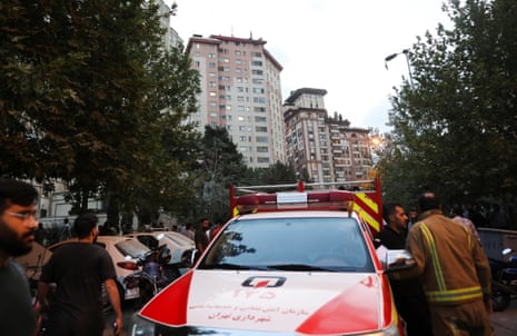 People gather in the street near an emergency vehicle in Tehran.