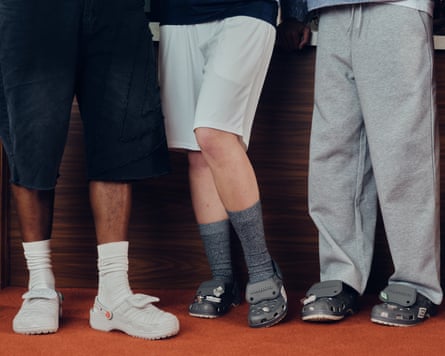 Four people standing from the waist-down, all wearing the Crocs and Umbro collab slides