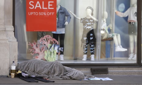 A person sleeps in front of a closed clothing shop in London