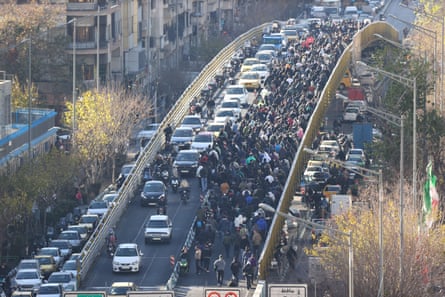 An entire lane of a dual carriage way is blocked by people walking along it in Tehran