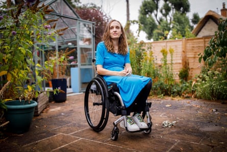 Lucy sits in her garden in a wheelchair in a blue dress