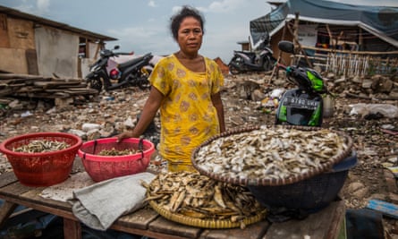 Johariah in front of her makeshift store selling salted fish near the remnants of what used to be her home.