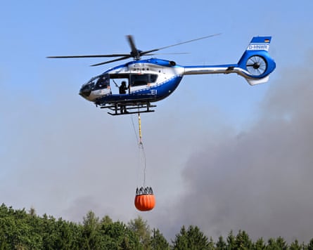 A police helicopter carries water to be dumped on wildfire in the Hürtgen forest in western Germany.