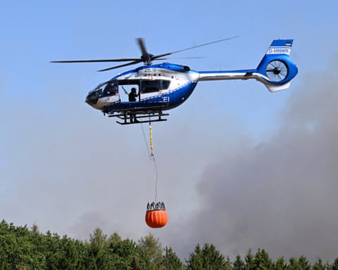 A police helicopter carries water to be dumped on wildfire in the Hürtgen forest in western Germany.