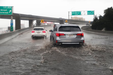 Cars drive through flood water on a ramp leading up to a highway
