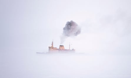 Black exhaust fumes are emitted from the funnel of a ship in fog 
