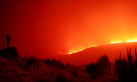 A man stands in the vicinity of wildfire, near Povoa de Montemuro, Portugal.