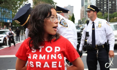 a women in a red shirt with hands and police officer behind her