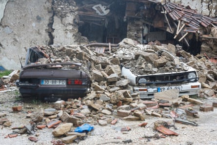 Two cars under rubble of collapsed building.