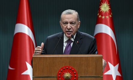 Turkish president Erdoğan speaking at a lectern between two Turkish flags