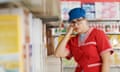 Tired supermarket employee leaning on a store shelf and resting
