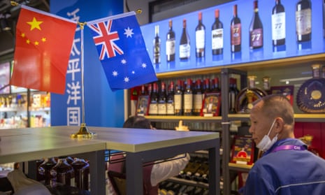 a man with a face mask in a bottle shop with shelves of wine and australian and chinese flags