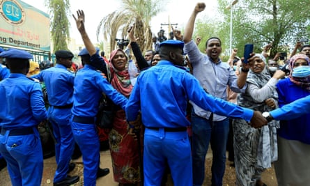 Sudanese police officers control civilians as they chant slogans outside court on Tuesday.