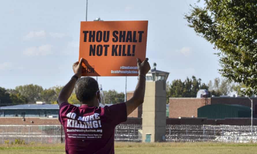 A protester holds a sign up across the street from the Federal Correctional Complex in Terre Haute, Indiana.