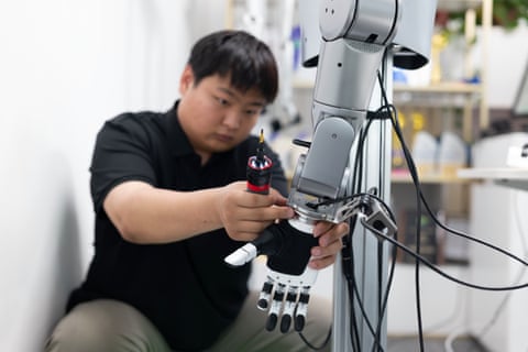 A technician calibrates a robotic dextrous hand mounted on a mechanical arm at Linkerbot