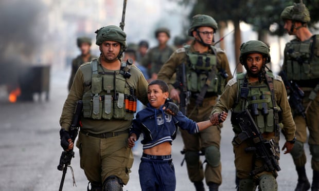 Israeli soldiers detain a Palestinian boy during clashes in the West Bank city of Hebron