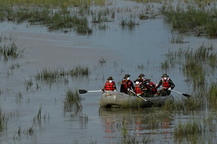 Members of army personnel row a boat on a river