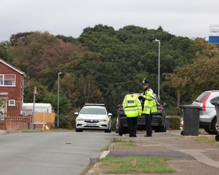 Police officers and a police car on a road in the village