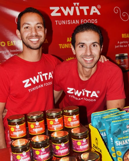 Two men grin while posing pinch jars of Zwïta-branded harissa and shakshuka