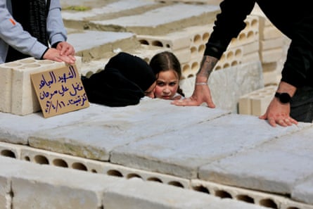 A woman and child crouch down next to a coffin