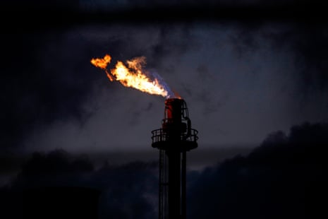 an oil rig with fire coming out the top photographed at night