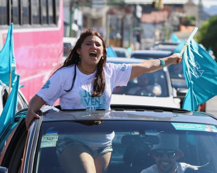Woman standing up in car with blue flags