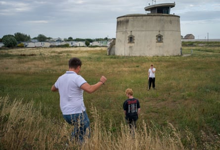 Three young men walk down a dune towards a round Napoleonic fort