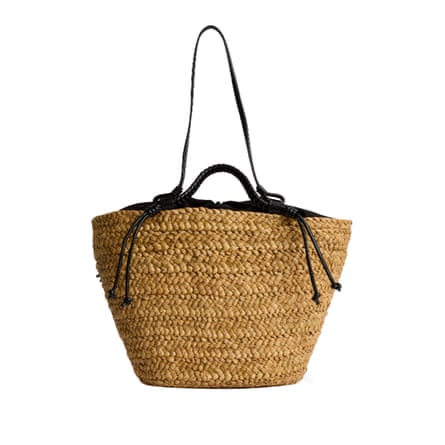 A woven straw basket bag with black leather handles