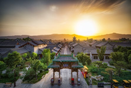 The sun sets behind a pagoda and other traditional buildings