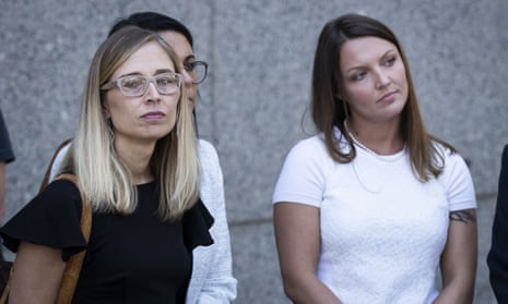 Two women, one blond and wearing glasses and a black top, the other brunette with a white top, stand outside a courthouse.