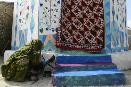 A resident paints her flood-resistant hut in Sanjar Chang.