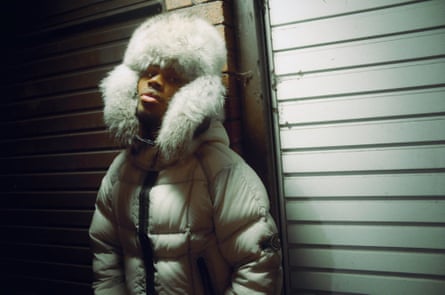 Jim Legxacy i veshur me një xhaketë puffer dhe kapelë me qime.