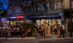 People socialise outside a bar in Paris as France prepares to close nightclubs in a bid to curb a surge in Covid-19 cases.