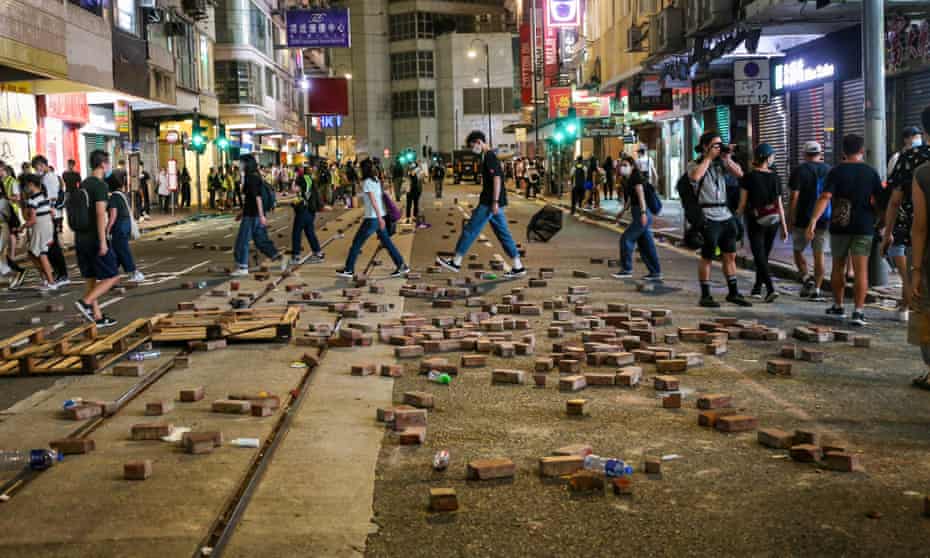 Hongkongers walk past bricks dug up and laid out on the street to slow down incoming police during demonstrations.
