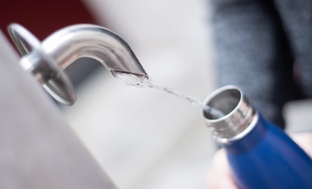 Woman pouring a natural mineral water in reusable bottles